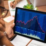 Man with his hand on his face looking at a falling share price chart on a tablet.