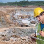 Miner on his tablet next to a mine site.