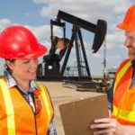 Two workers at an oil rig discuss operations.