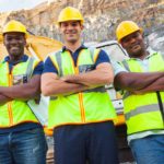 Three satisfied miners with their arms crossed looking at the camera proudly