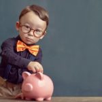 Kid putting a coin in a piggy bank.