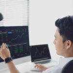 A share market analyst looks at his computer screen in front of him showing ASX share price movements