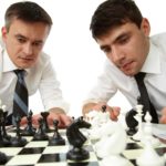 Two men in business attire play chess.