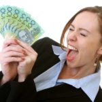 A woman looks excited as she fans out a wad of Aussie $100 notes.