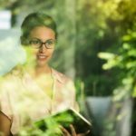 A businesswoman looks out a window at a green, environmental project.