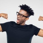 A guy wearing glasses tries to show off his muscles.