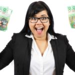 A woman looks excited as she holds Australian dollars in the air.