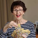A woman holds out a handful of Australian dollars.