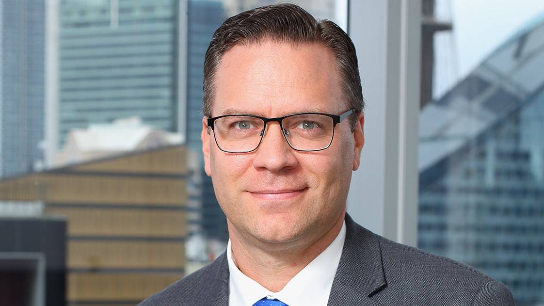 A portrait shot of Adrian Ezquerro in an office setting with skyscrapers in the background.