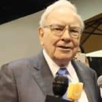 A head shot of legendary investor Warren Buffett speaking into a microphone at an event.