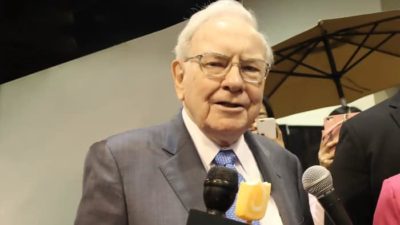 A head shot of legendary investor Warren Buffett speaking into a microphone at an event.