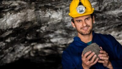 A coal miner smiling and holding a coal rock, symbolising a rising share price.