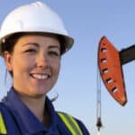 Female oil worker in front of a pumpjack.