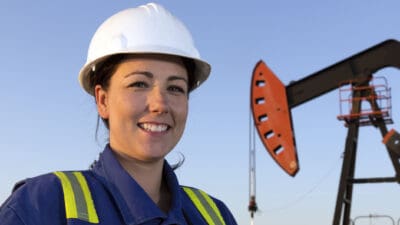 Female oil worker in front of a pumpjack.