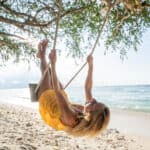 Woman on a swing at a beach, symbolising passive income.