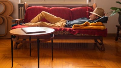 person laying on a couch with a hat, symbolising passive income.