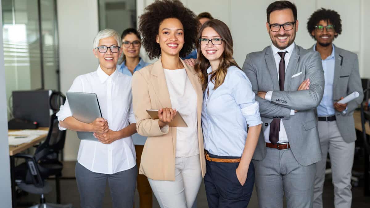 A group of work colleagues standing together and smiling, symbolising diversification.