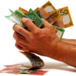 Person with a handful of Australian dollar notes, symbolising dividends.