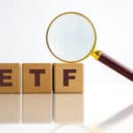 ETF written on wooden blocks with a magnifying glass.