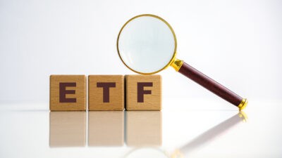 ETF written on wooden blocks with a magnifying glass.