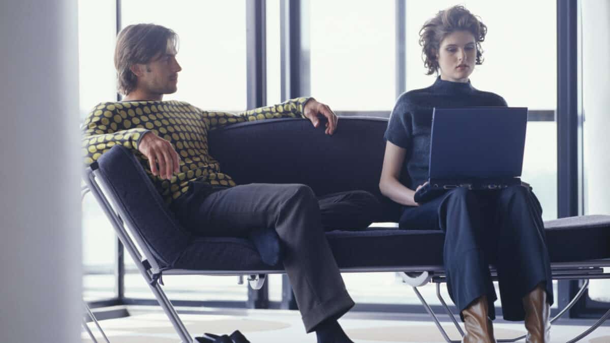 Couple waiting for their flight at an airport with the woman on a laptop.