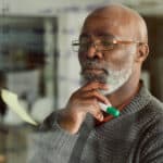 Cropped shot of a mature businessman brainstorming and setting financial goals with notes on a glass wall.