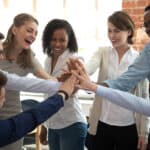 Happy diverse colleagues or team of people give high five together to celebrate great teamwork and results.