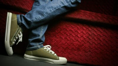 A Teenager showing his/her shoes and jeans, posing in studio.