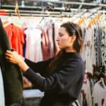 Vintage toned portrait of a young beautiful brunette woman in London second hand marketplace. She is wearing casual clothes, black knitted sweater, looking through the second hand market stalls.