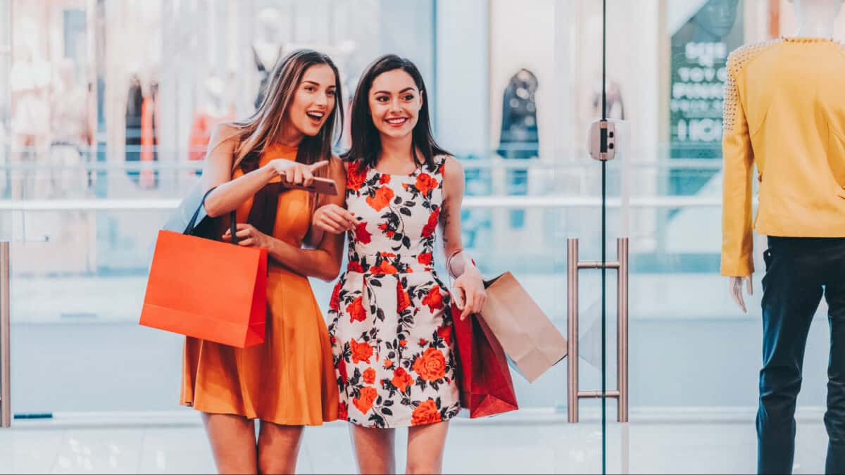 Two woman shopping and pointing at a bargain opportunity.