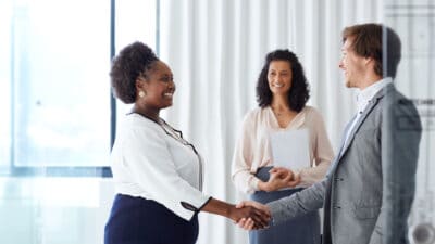 Three smiling people shake hands to seal the deal.