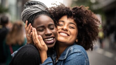 Two close female friends hug each other and smile after receiving good news.