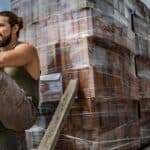 A brickie sits next to a pile of bricks all stacked up and ready to lay.