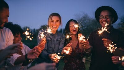 Five young people celebrate outside with sparklers