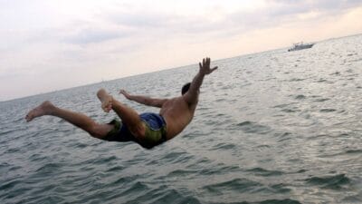 A man dives off a boat into the sea, indicating a share price fall