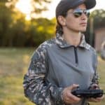 A female soldier flies a drone using hand-held controls.