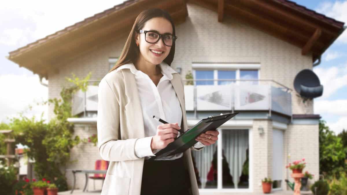 Happy woman standing in front of a house with a pen and clipboard.