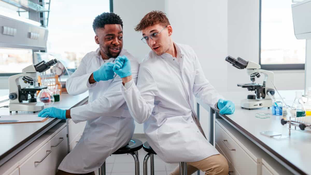 Two lab workers fist pump each other.