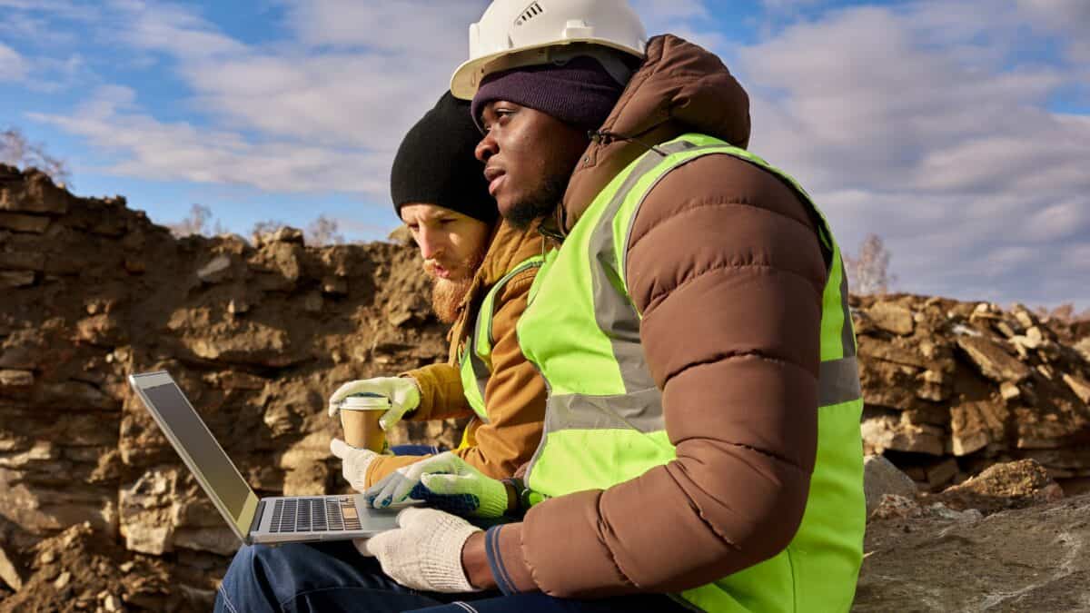 Two mining workers on a laptop at a mine site.