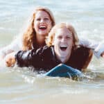 A happy laughing surfer couple surfing together.