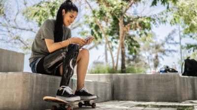 Disabled skateboarder woman using mobile phone at the park.