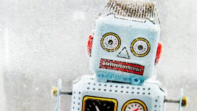 A robot grimaces and looks alarmed as it sits frozen in ice.
