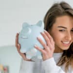 Happy young woman saving money in a piggy bank.