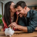 Happy young couple saving money in piggy bank.