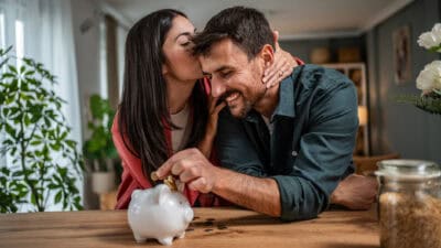 Happy young couple saving money in piggy bank.