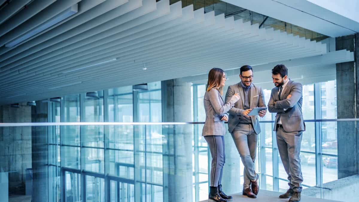 Group of successful real estate agents standing in building and looking at tablet.