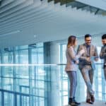 Group of successful real estate agents standing in building and looking at tablet.