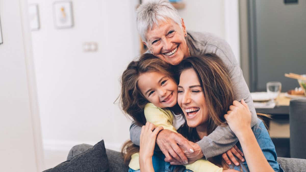 Three generation of women cuddling and smiling together.