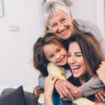 Three generation of women cuddling and smiling together.