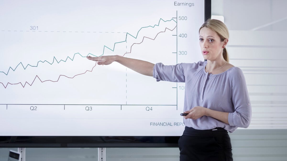 Woman presenting financial report on large screen in conference room.